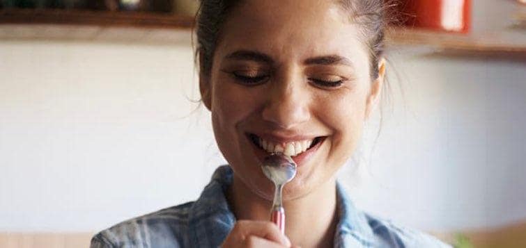 Jeune femme souriante avec une cuillère à la bouche